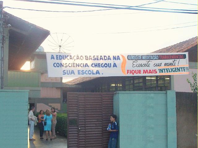 12Brasil - Sete Lagoas.jpg - Teachers of the Transcendental Meditation Technique speak with teachers outside the school, where banners proudly announce that at this school Consciousness-Based Education is taught, and that Transcendental Meditation increases the students’ intelligence.